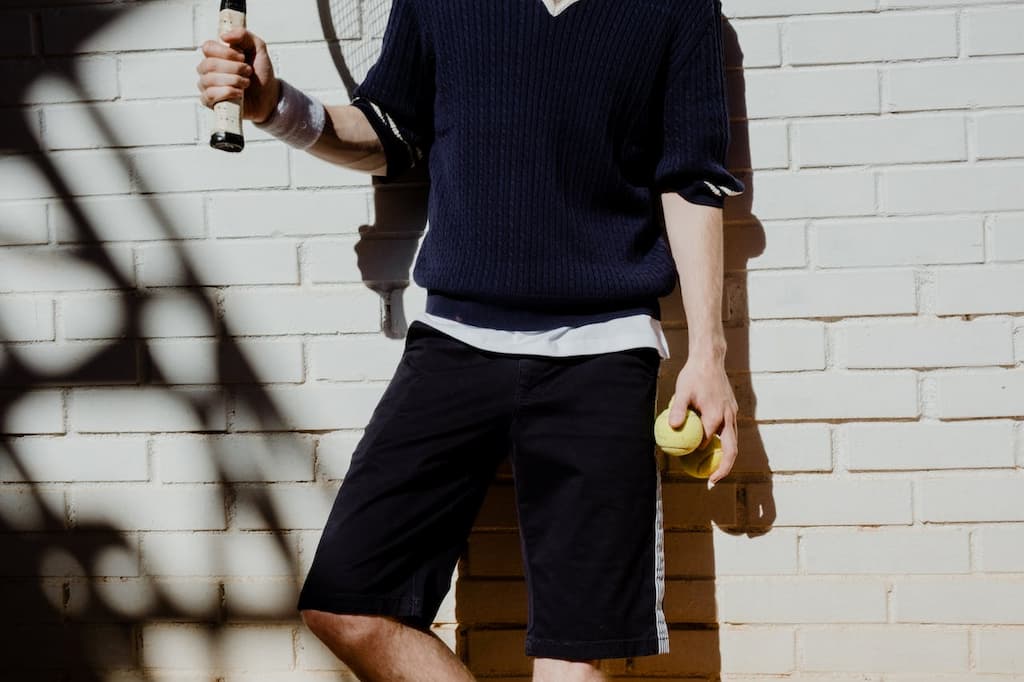 Man holding Padel balls and racket leaned to the wall