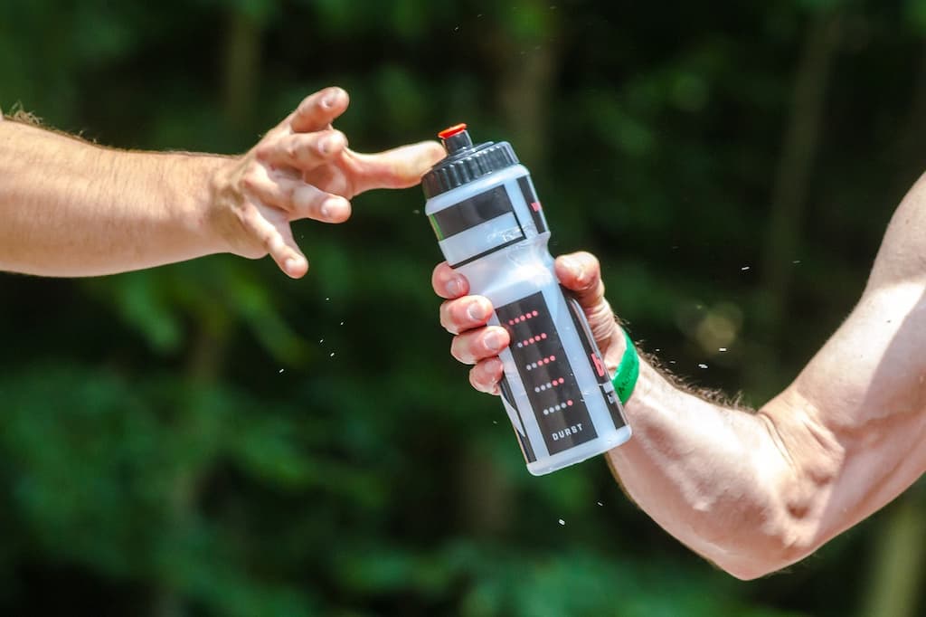 Man passing water bottle to another man